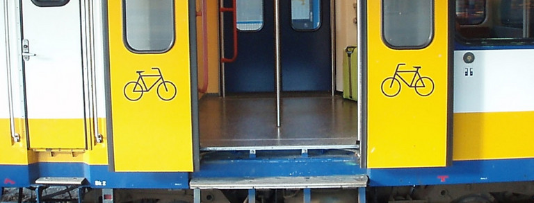 Studenten im Sommer auf dem Campus Nord, rote Zahnräder im Hintergrund
