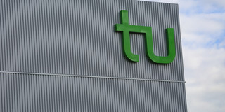Das große Logo der TU an einem Gebäude.